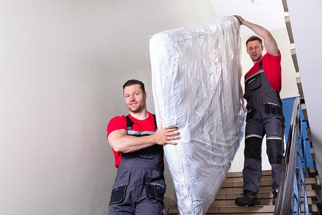 two workers lifting a box spring out of a bedroom in Eminence